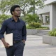 Un jeune homme marche dans une cour avec un dossier sous le bras.
